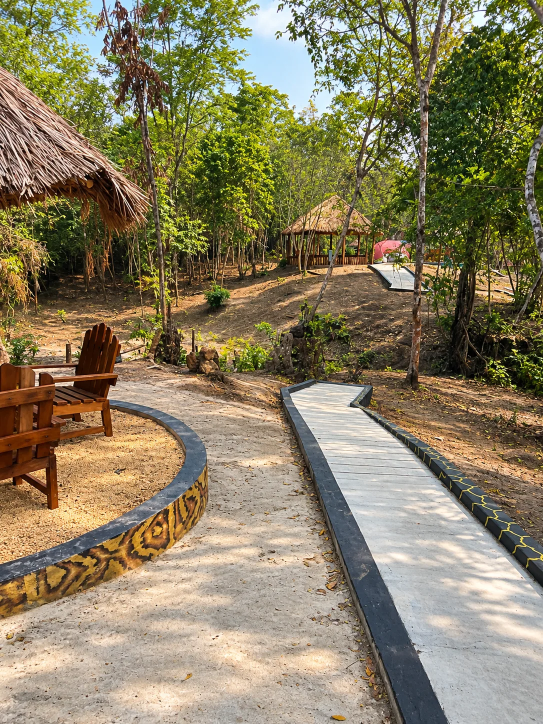 A winding walkway between thatched garden shelters